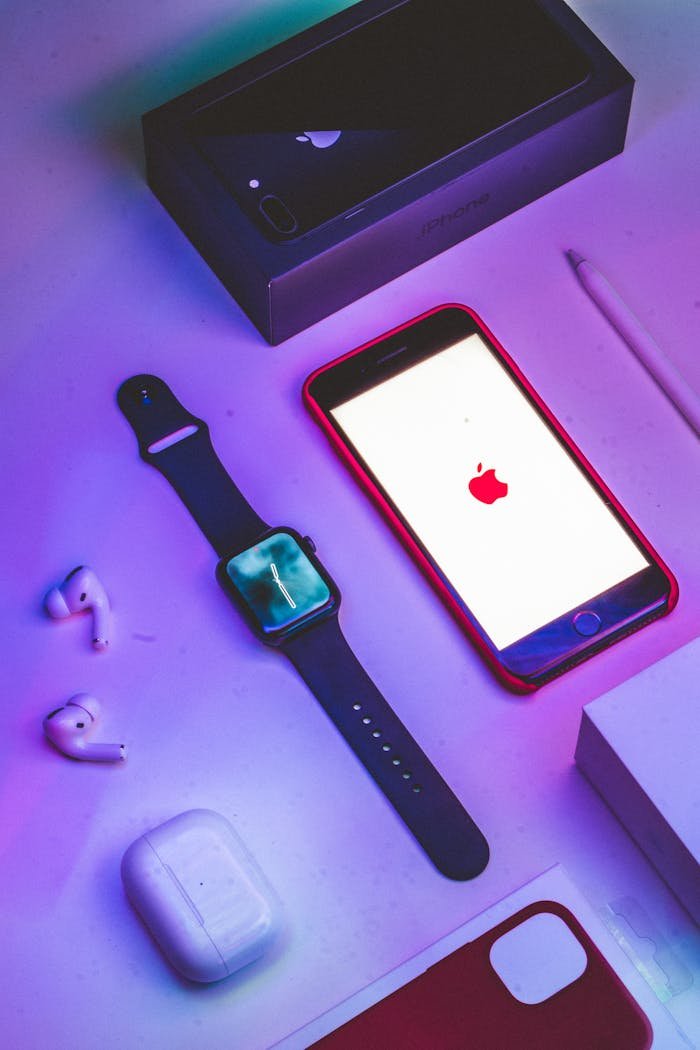 Modern Apple gadgets including watch and phone displayed under colorful lighting for tech enthusiasts.